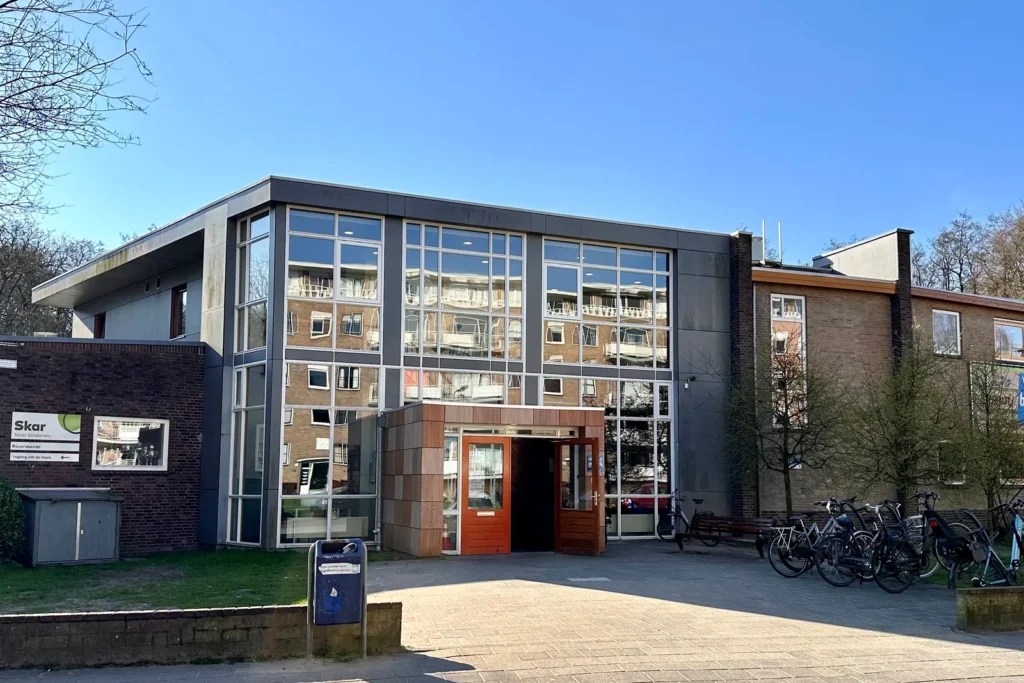Schoolgebouw in Arnhem met glazen entreepartij, gezien vanaf de straatzijde