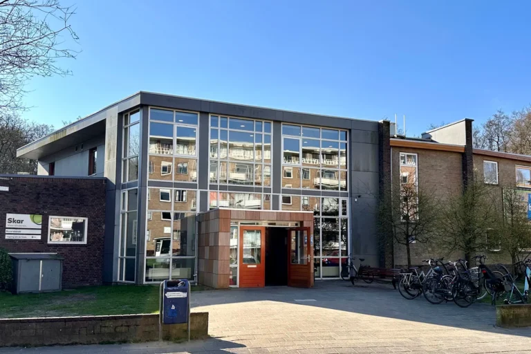 Schoolgebouw in Arnhem met glazen entreepartij, gezien vanaf de straatzijde